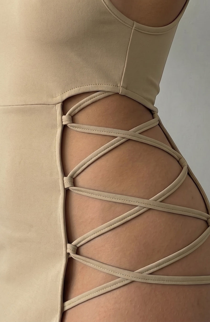 LORVENE beige mini dress with a flattering fit and intricate strappy side cutouts. Smooth drape fabric.