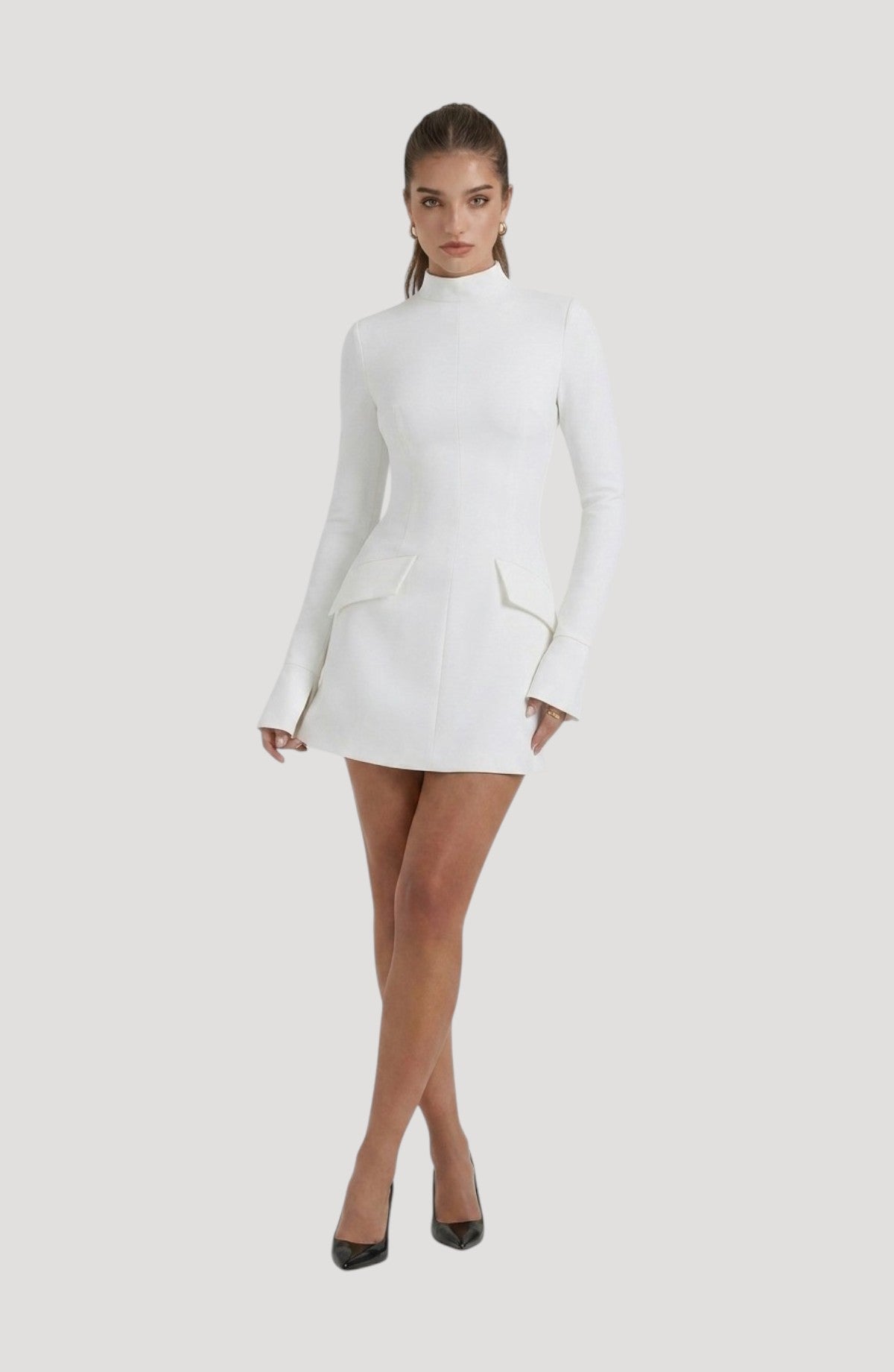 LORVENES white long-sleeve mini dress with mock neck and flap pockets. Model wears black heels.