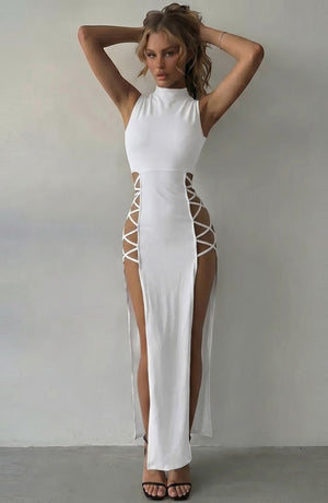 LORVENE white sleeveless mock neck maxi dress with daring lace-up side cutouts and high slits. Model wears heels.